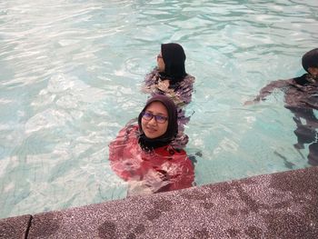 Friends wearing hijab swimming in infinity pool