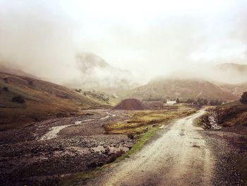 Scenic view of road by mountains against sky