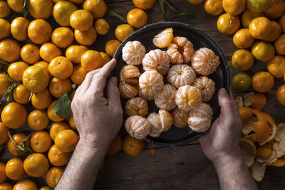 Cropped hands of man peeling orange fruits