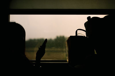 Silhouette people sitting in car against sky