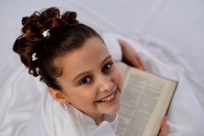 Close-up portrait of smiling girl with book at home