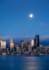 A bright full moon shines over the seattle skyline.