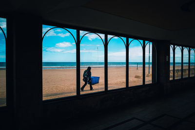 Rear view of man standing at beach against sky