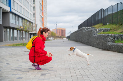 Woman with dog on footpath in city