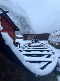Snow covered houses by buildings against sky