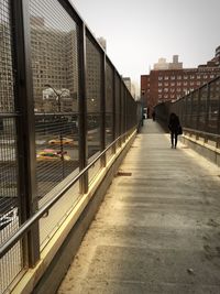 Man walking in city against sky