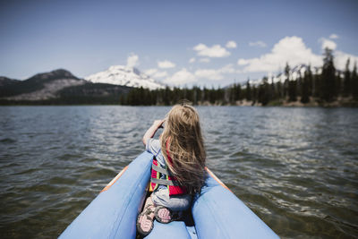 Rear view of girl sitting in inflatable raft on lake