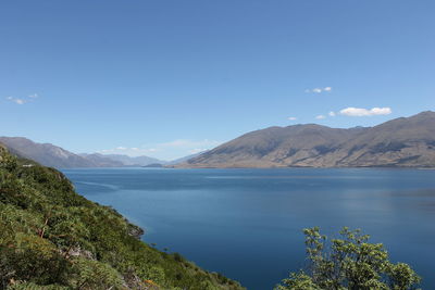 Scenic view of lake and mountains against blue sky