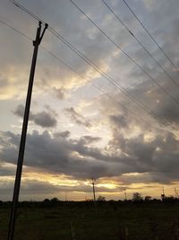 Low angle view of silhouette electricity pylon on field against sky