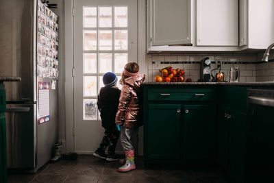 Young brother and sister wearing jackets waiting to go outside