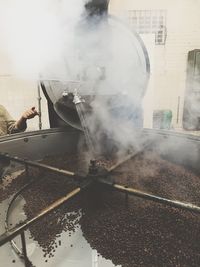 Cropped image of worker cleaning coffee crops in factory container