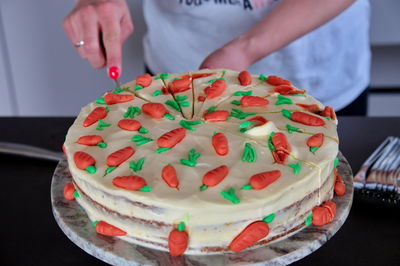 Womans hands cutting decorated birthday cake on black table