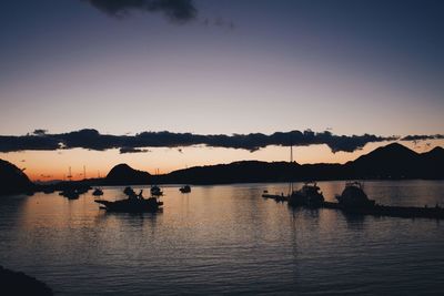 Silhouette boats in lake against sky during sunset