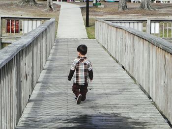 Rear view of boy walking on railing