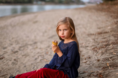 Portrait of girl eating ice cream sitting on lakeshore
