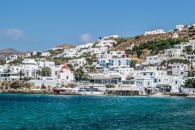 Buildings by sea against blue sky