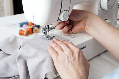 Cropped hands of craftswoman sewing textile on machine at workshop