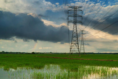 Electricity pylon on field against sky