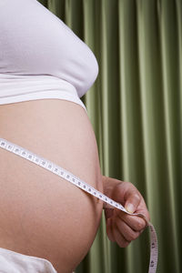 Close-up of pregnant woman measuring abdomen