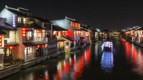 Canal amidst illuminated buildings in city at night