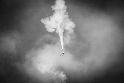 Low angle view of airplane flying against cloudy sky