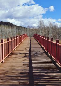 Boardwalk on footbridge against sky