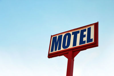 Low angle view of road sign against clear blue sky