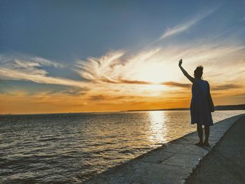 Rear view of man standing at sea shore against sky