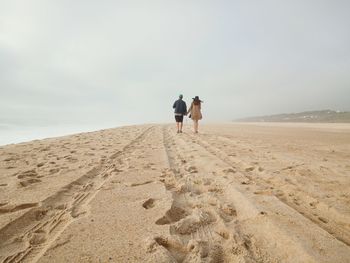 Rear view of people walking on beach