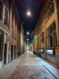 Empty road along buildings at night