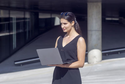 Portrait of young woman using mobile phone while standing in gym