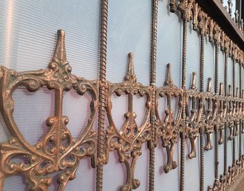 Close-up of chain hanging on metal fence against building