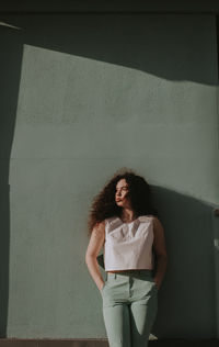 Woman with curly hair standing against wall