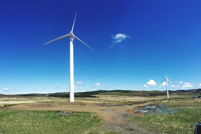 Windmill on field against blue sky