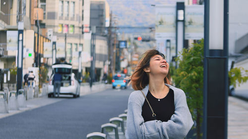 Young woman looking away while standing in city