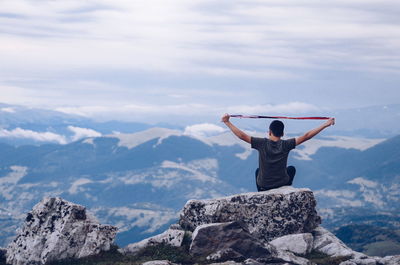 Rear view of boy looking at landscape while sitting on mountain