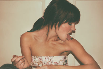 Woman sticking out tongue at home