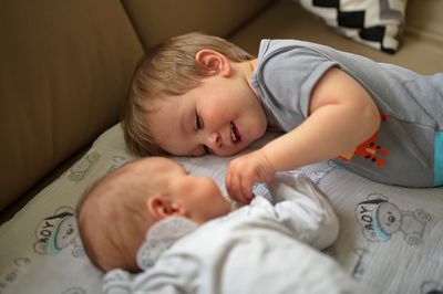 Cute little toddler and his newborn baby sister on the sofa