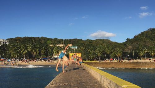 Men standing at beach against sky