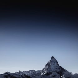 Snowcapped mountain against clear blue sky at dusk