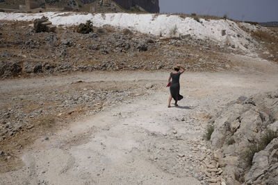 Rear view full length of woman walking on field during sunny day