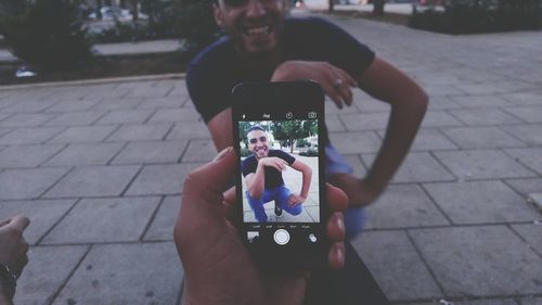 Man photographing woman using mobile phone