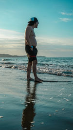 Shirtless man standing at beach against sky