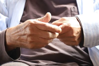 Midsection of senior man fist bumping with doctor in hospital