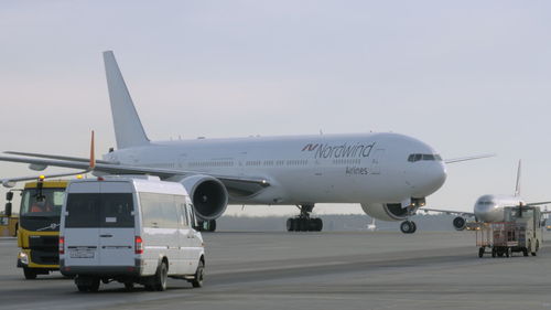 Airplane on airport runway against sky