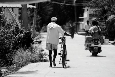 Rear view of man riding bicycle on road