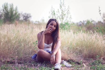 Portrait of smiling young woman sitting on field