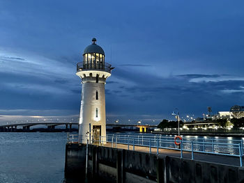 Lighthouse by sea against dark evening sky at dusk with no people