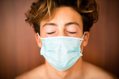 Close-up of teenage boy with eyes closed wearing mask