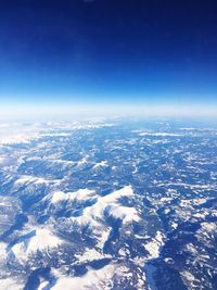 Aerial view of sea and landscape against blue sky